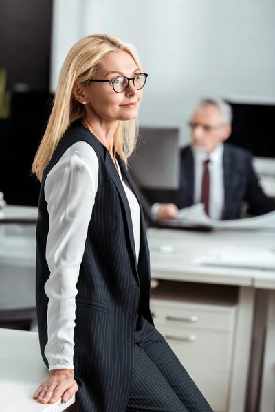 Вибірковий фокус щасливої бізнес-леді в окулярах, що стоять біля бізнесмена — стокове фото