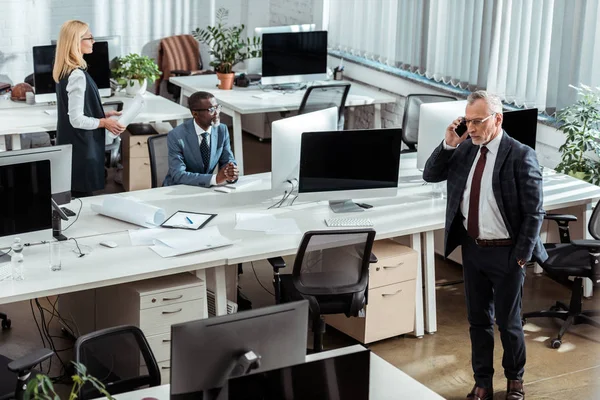 Overhead-Ansicht eines Geschäftsmannes, der in der Nähe multikultureller Mitarbeiter im Büro mit dem Smartphone spricht — Stockfoto