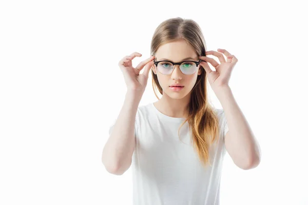Seria ragazza adolescente toccare gli occhiali e guardando la fotocamera isolata su bianco — Foto stock