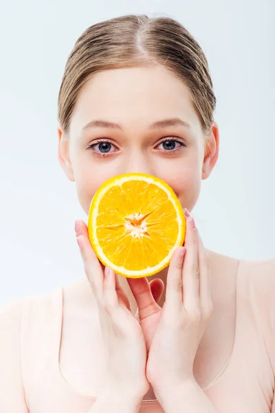 Teenage girl holding ripe orange in front of mouth isolated on grey — Stock Photo