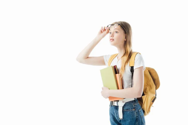 Цікава школярка з рюкзаком тримає книги і дивиться ізольовано на білому — стокове фото