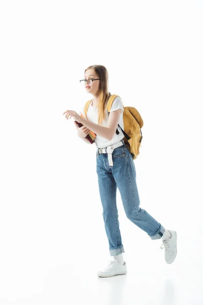 Colegiala en gafas con mochila sosteniendo libros y caminando aislado en blanco - foto de stock