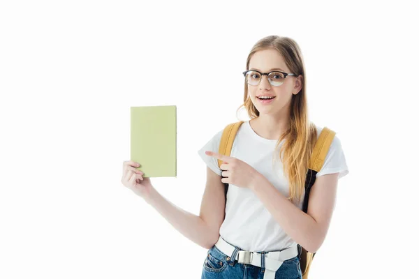 Усміхнена школярка з рюкзаком вказує пальцем на книгу ізольовано на білому — стокове фото