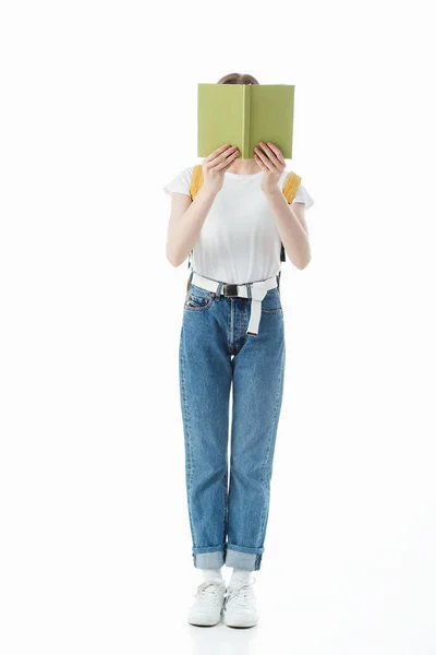 Scolaretta con zaino in mano libro davanti al viso isolato su bianco — Foto stock