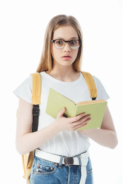 Schockierte Schülerin mit Rucksack hält Buch isoliert auf weißem Papier — Stockfoto