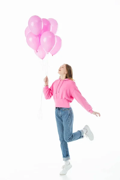 Visão de comprimento total da menina adolescente feliz olhando para balões rosa isolado no branco — Fotografia de Stock