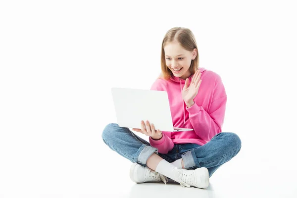 Heureuse adolescente souriante agitant la main dans l'écran de l'ordinateur portable pendant le chat vidéo isolé sur blanc, éditorial illustratif — Photo de stock