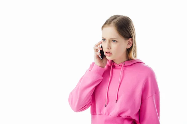Upset teenage girl in pink hoodie talking on smartphone isolated on white — Stock Photo
