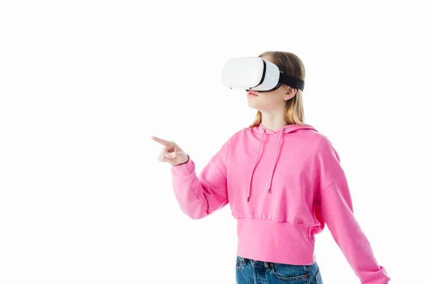 Teenage girl in pink hoodie wearing vr headset and pointing with finger isolated on white — Stock Photo