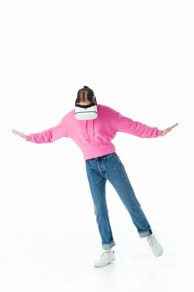 Adolescente en sudadera con capucha rosa y pantalones vaqueros azules con auriculares vr y gestos aislados en blanco - foto de stock