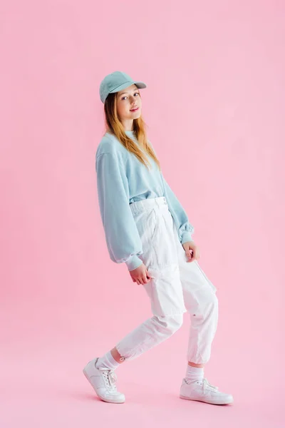 Menina bonita elegante adolescente em boné olhando para a câmera em rosa — Fotografia de Stock