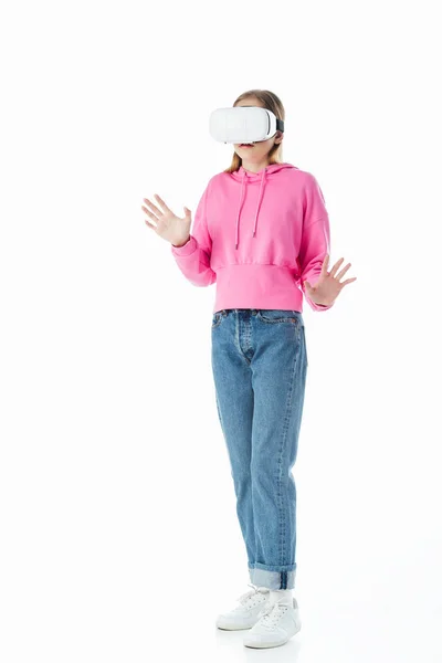 Menina adolescente com capuz rosa e jeans vestindo vr fone de ouvido e gesto isolado no branco — Fotografia de Stock