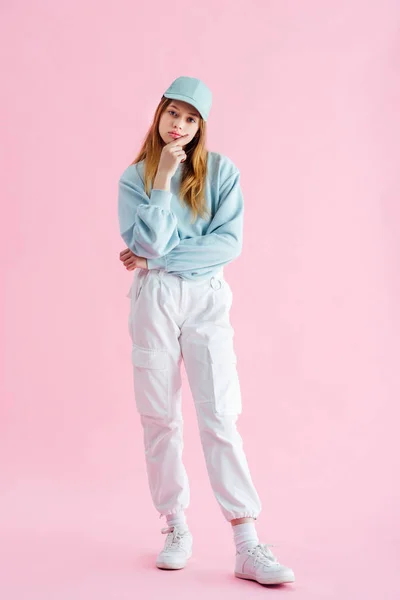 Full length view of sad pretty teenage girl in cap on pink — Stock Photo