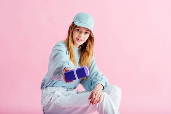 Pretty teenage girl in cap isolated on pink — Stock Photo