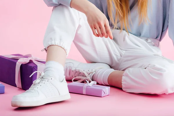 Cropped view of teenage girl sitting near presents on pink — Stock Photo