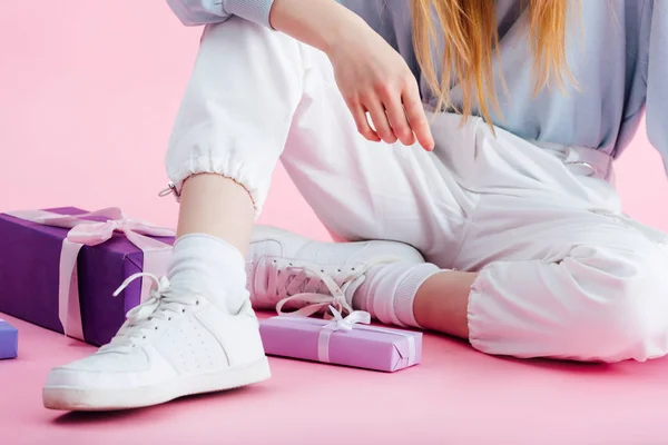 Vista cortada de adolescente sentada perto de presentes em rosa — Fotografia de Stock