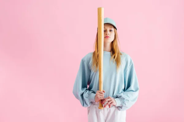 Pretty teenage girl in cap holding baseball bat isolated on pink — Stock Photo
