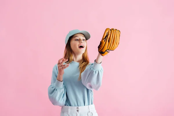 Excitado bastante adolescente en gorra celebración de guante de béisbol aislado en rosa - foto de stock