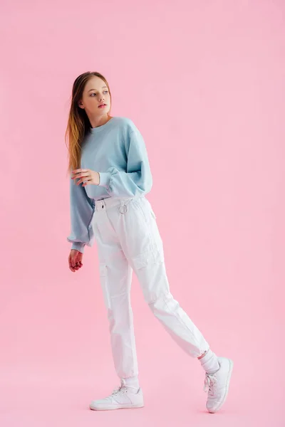 Full length view of pretty teenage girl looking away on pink — Stock Photo