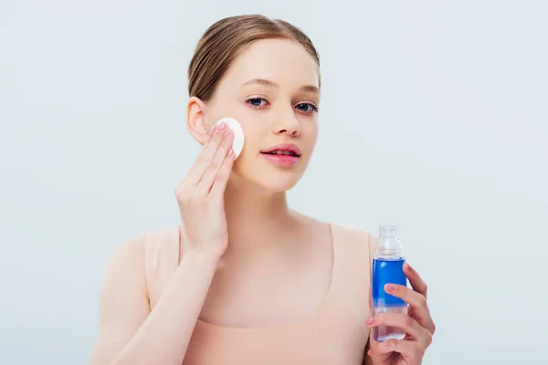 Hübsche Teenager-Mädchen Anwendung Lotion auf das Gesicht mit Wattepad isoliert auf grau — Stockfoto