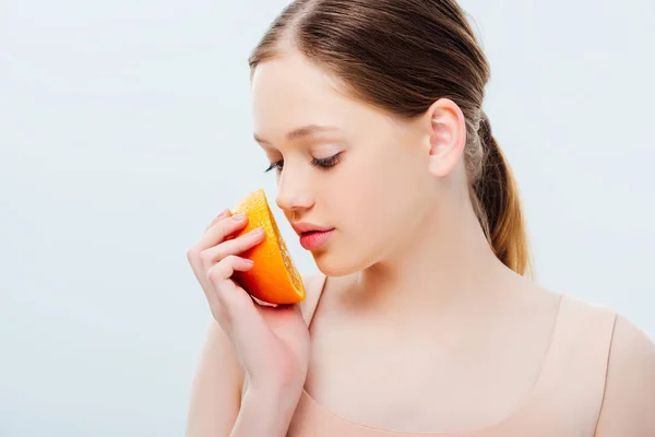 Hermosa adolescente mirando maduro naranja medio aislado en gris - foto de stock