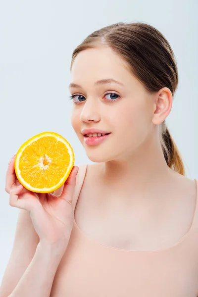 Smiling beautiful teenage girl holding ripe orange half isolated on grey — Stock Photo