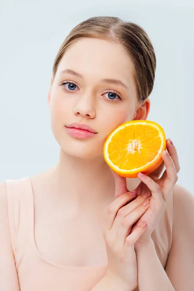 Beautiful teenage girl holding ripe orange half isolated on grey — Stock Photo