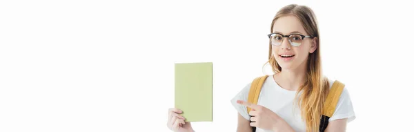 Écolière souriante avec sac à dos pointant du doigt au livre isolé sur blanc, plan panoramique — Photo de stock