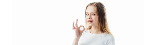Щаслива дівчина-підліток, що показує знак ОК ізольовано на білому, панорамний постріл — стокове фото