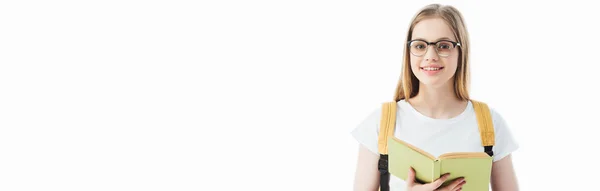 Sonriente colegiala con mochila celebración libro aislado en blanco, tiro panorámico - foto de stock