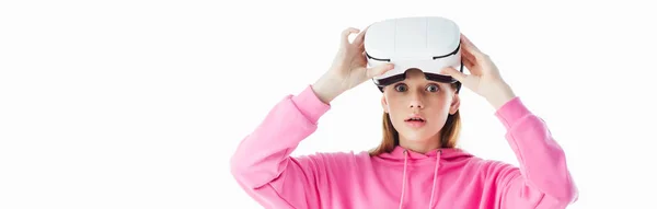 Panoramic shot of shocked teenage girl in pink hoodie wearing vr headset isolated on white — Stock Photo