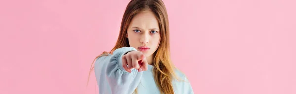 Plano panorámico de triste adolescente apuntando con el dedo a la cámara aislado en rosa - foto de stock