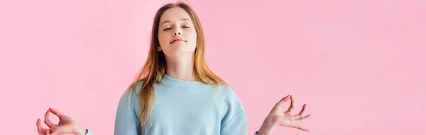 Plano panorámico de chica adolescente bonita con los ojos cerrados meditando aislado en rosa - foto de stock