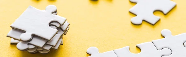 Panoramic shot of stacked white puzzle pieces on yellow — Stock Photo