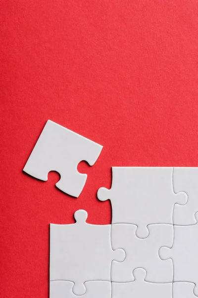 Top view of unfinished white jigsaw puzzle pieces isolated on red — Stock Photo