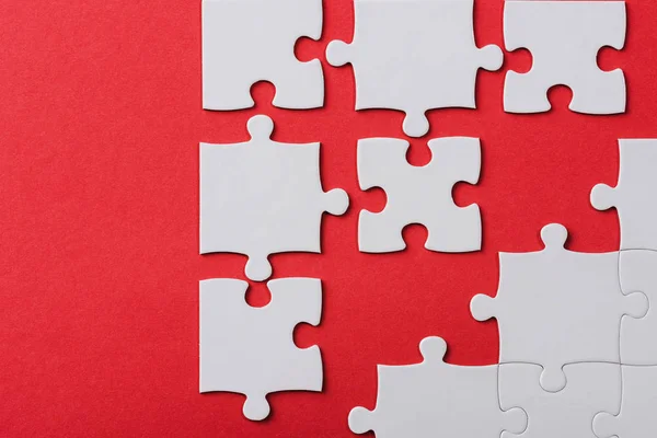 Top view of unfinished jigsaw puzzle pieces isolated on red — Stock Photo