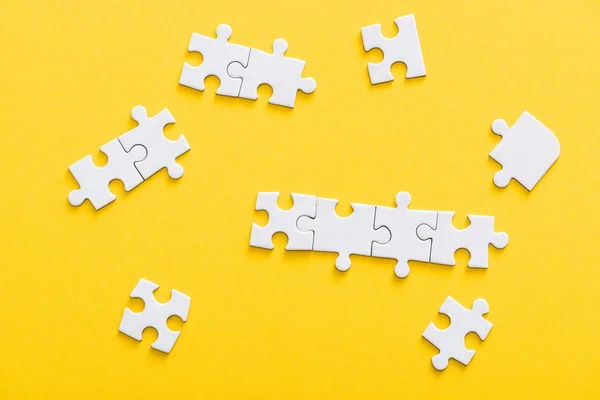 Top view of connected jigsaw puzzle pieces isolated on yellow — Stock Photo