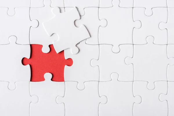 Top view of white incomplete jigsaw near puzzle piece — Stock Photo