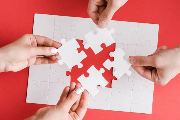 Top view of man and woman holding white puzzle pieces on white — Stock Photo