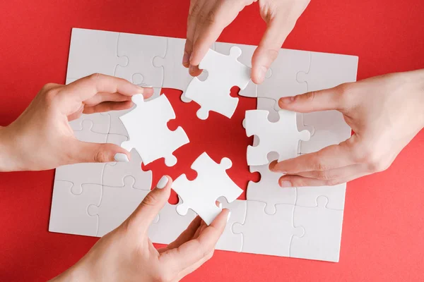 Top view of woman and man holding white puzzle pieces on white — Stock Photo