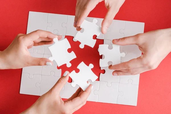 Vista dall'alto di donna e uomo in possesso di pezzi di puzzle bianchi su bianco — Foto stock