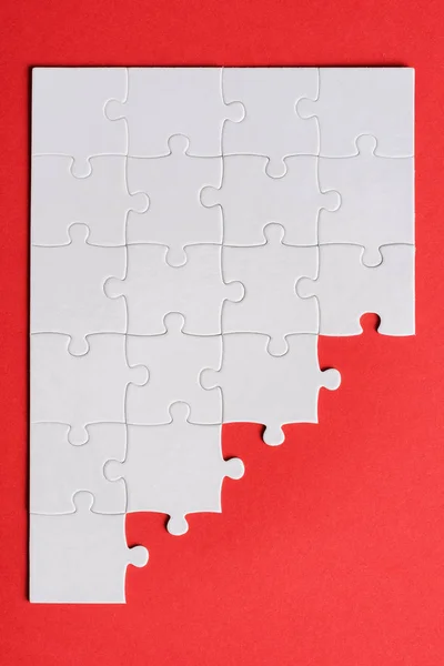 Top view of white connected puzzle pieces isolated on red — Stock Photo