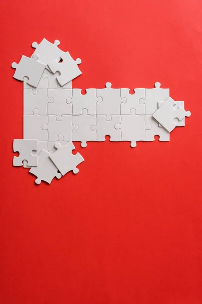 Top view of white connected puzzle pieces near shapes on red — Stock Photo