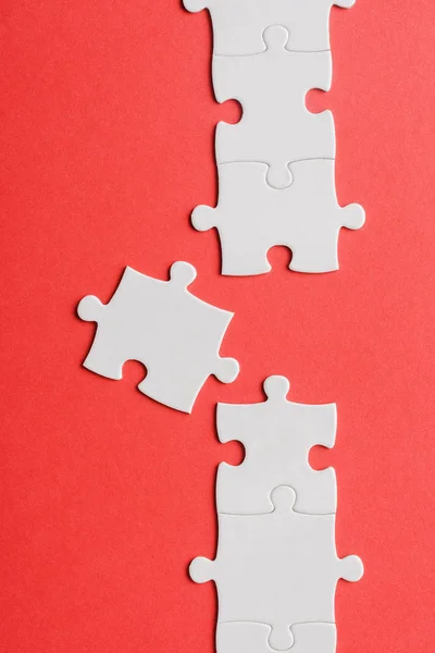 Top view of white connected jigsaw near puzzle piece isolated on red — Stock Photo