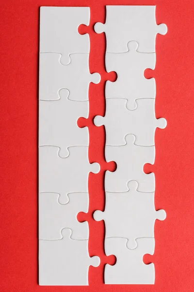 Vue de dessus des lignes blanches de pièces de puzzle connecté sur rouge — Photo de stock