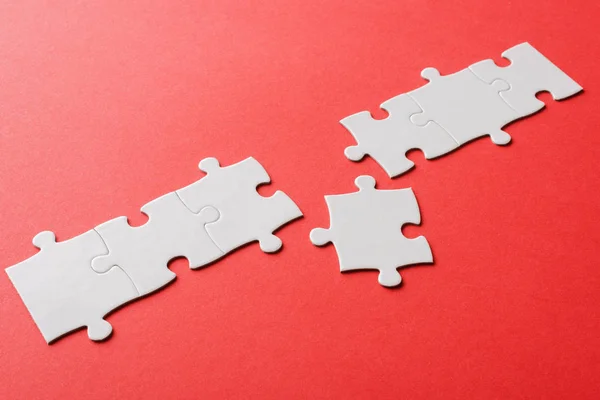 Puzzle connecté blanc près pièce de puzzle sur rouge — Photo de stock