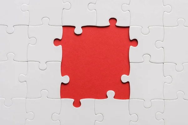 Top view of unfinished white jigsaw isolated on red — Stock Photo