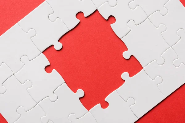 Top view of unfinished white jigsaw puzzles isolated on red — Stock Photo