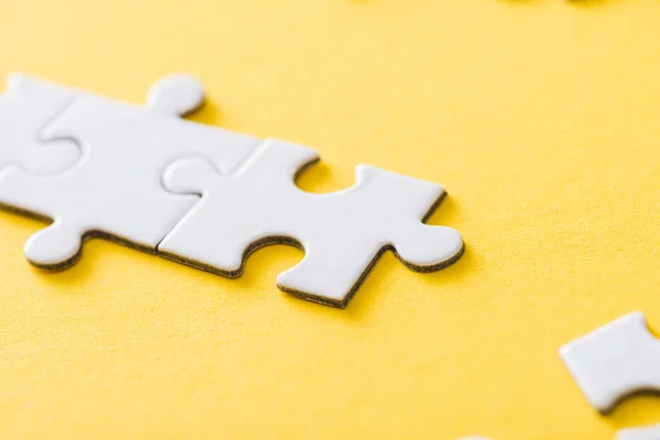 Selective focus of connected white puzzle pieces on yellow — Stock Photo