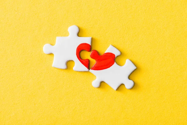 Top view of jigsaw puzzle pieces with drawn red heart isolated on yellow — Stock Photo